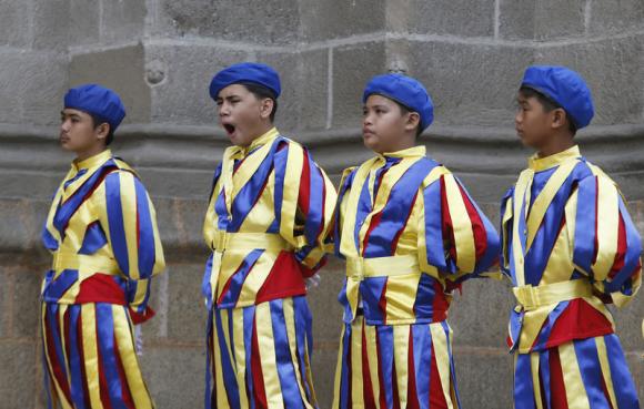A boy yawns as schoolchildren dressed as Vatican Swiss guards rehearse outside the Manila Cathedral for the upcoming papal visit in Manila